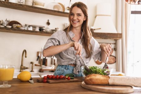 Image of young smiling concentrated happy positive cute beautiful woman indoors at the kitchen cooking.