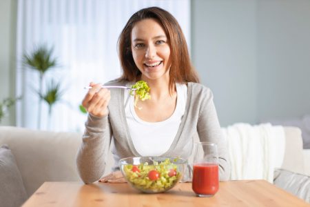 Portrait of an attractive young woman eating a salad in living room